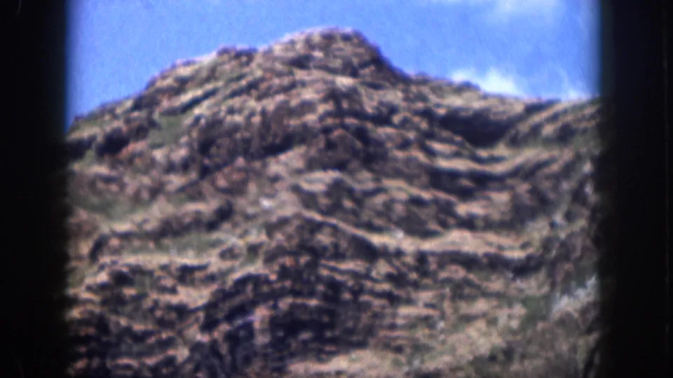 1959 Hawaii home-movie view of a rugged rocky hill rising beneath a clear blue sky.