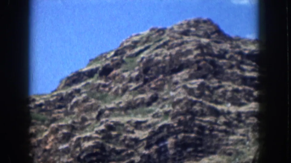 1959 Hawaii 8mm landscape frame with a rough hillside, scattered vegetation, and clear sky.