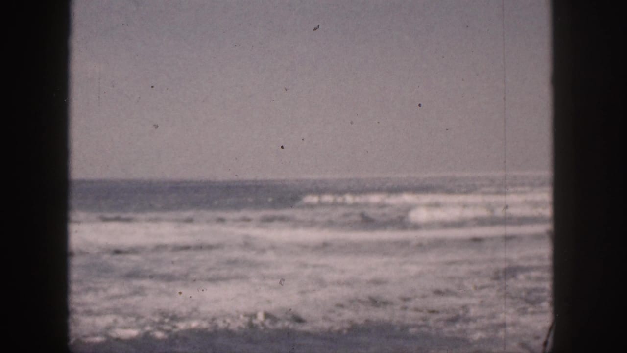 Foamy ocean whitecaps beyond a dark central window bar and side framing.