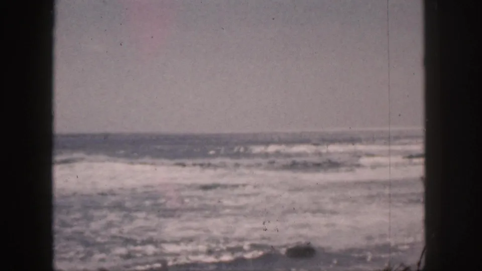 Faded 8mm Hawaii footage from 1959 showing rough ocean water and white surf bands through a dark window-like frame.