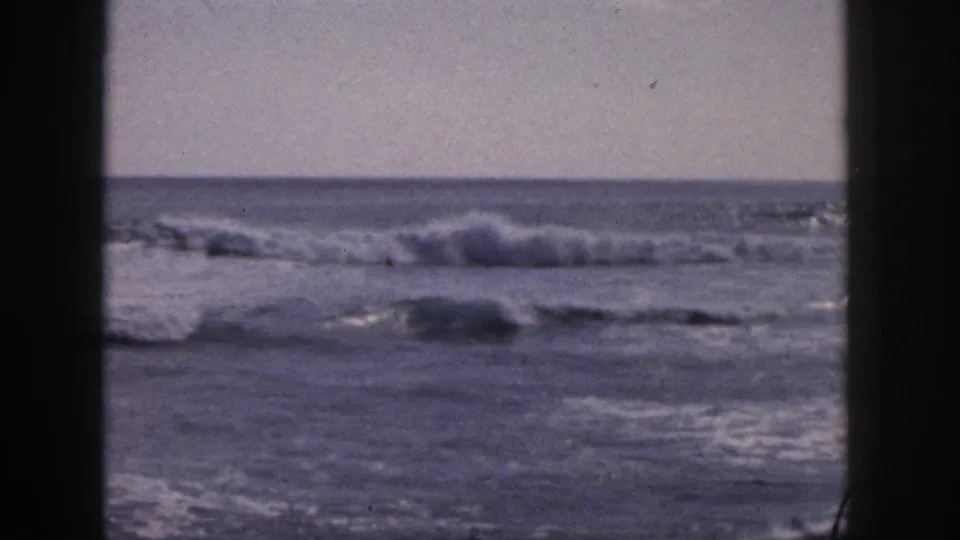 1959 Hawaii 8mm view of rolling ocean surf under a pale sky, framed by dark film-gate edges.