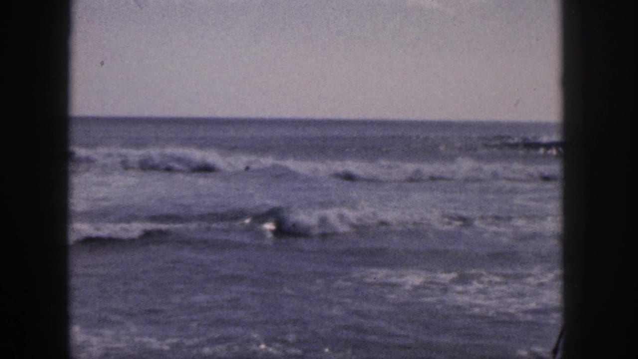 Soft, grainy view of waves breaking across the middle distance with dark borders at the sides.