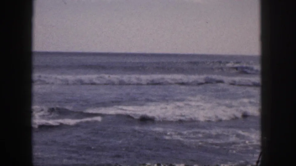 1959 Hawaii 8mm view of gentle surf and a flat sea horizon, with visible grain and gate borders.