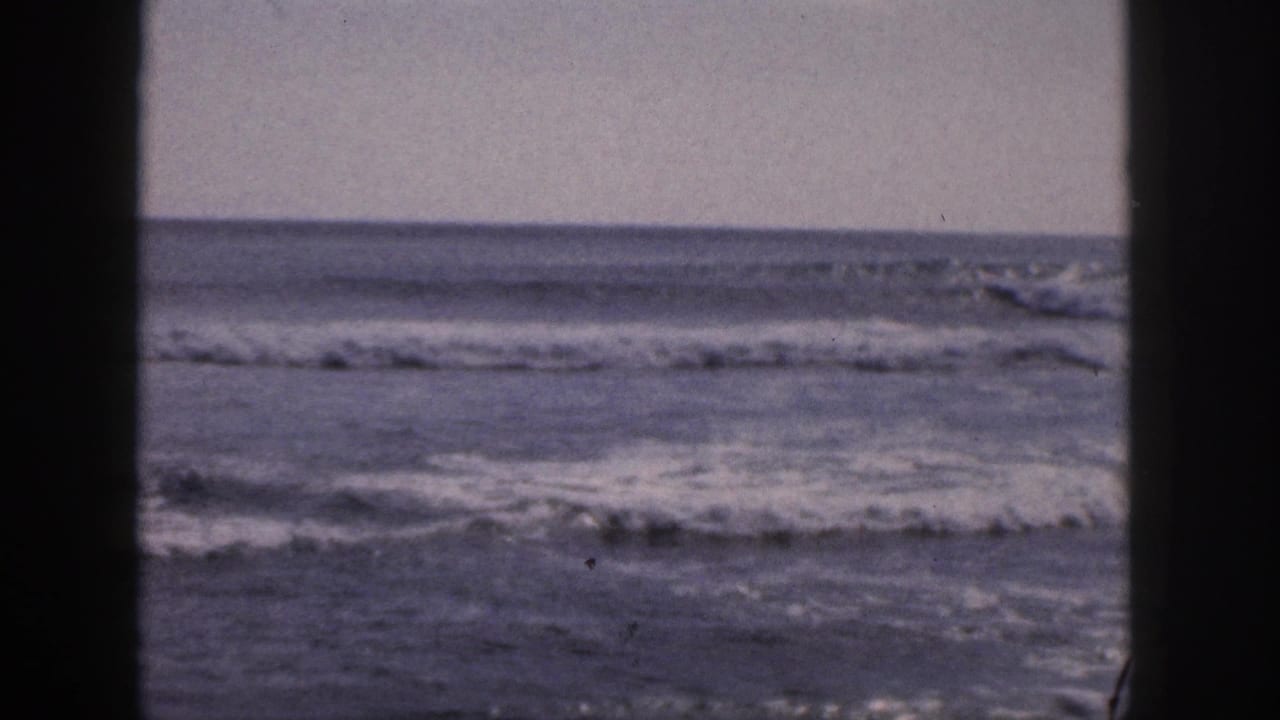 1959 Hawaii 8mm frame showing breaking ocean surf through a dark vertical window or doorway edge.