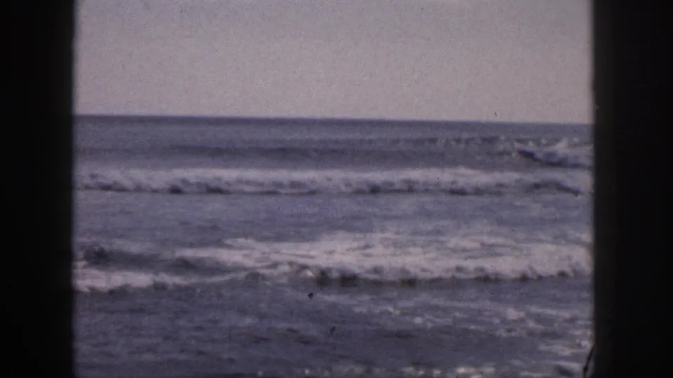 1959 Hawaii 8mm frame showing breaking ocean surf through a dark vertical window or doorway edge.