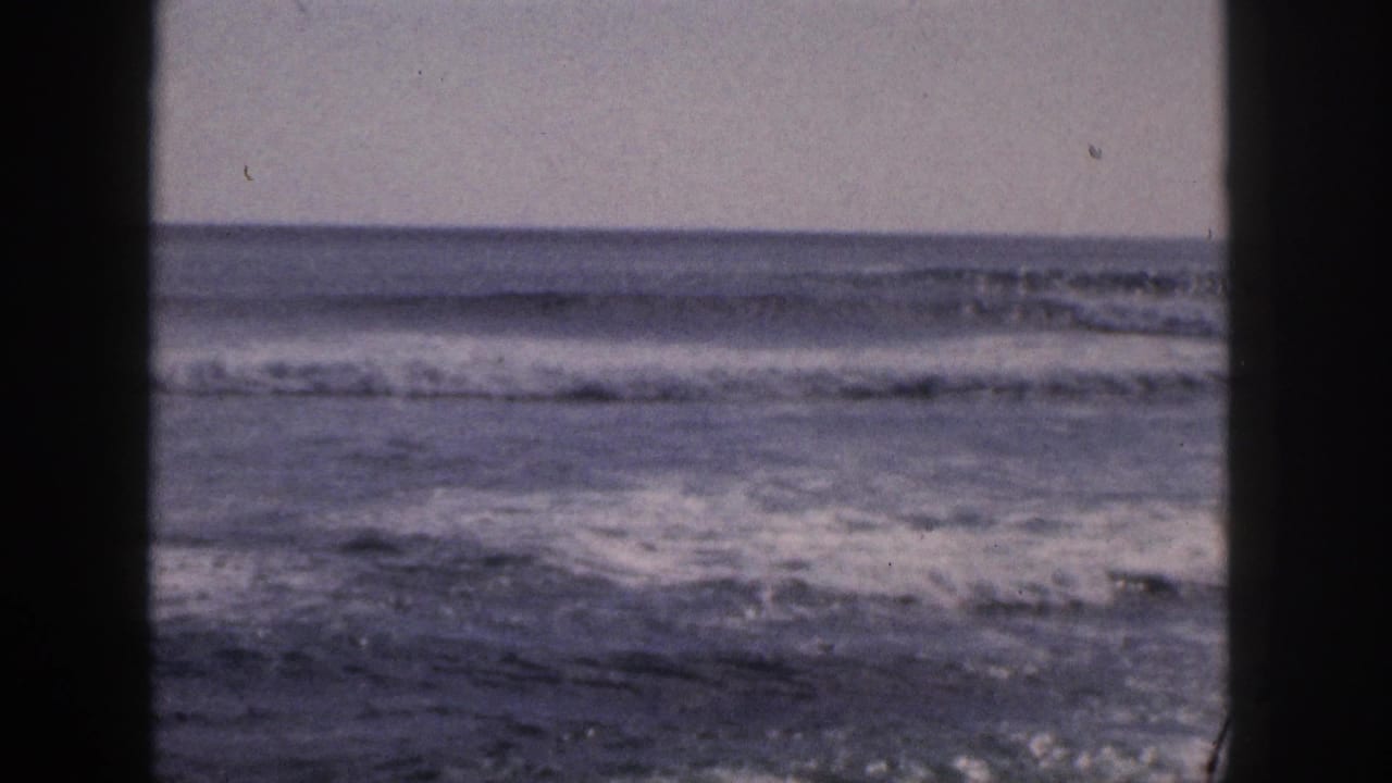Breaking surf and distant horizon divided by a dark central vertical frame.