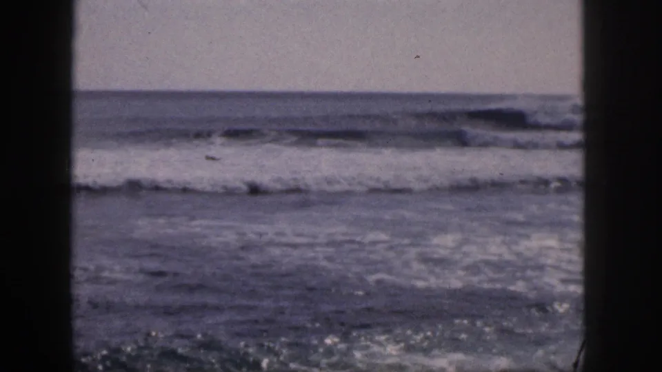 1959 Hawaii 8mm frame showing choppy surf and a low horizon through dark window-like vertical edges.