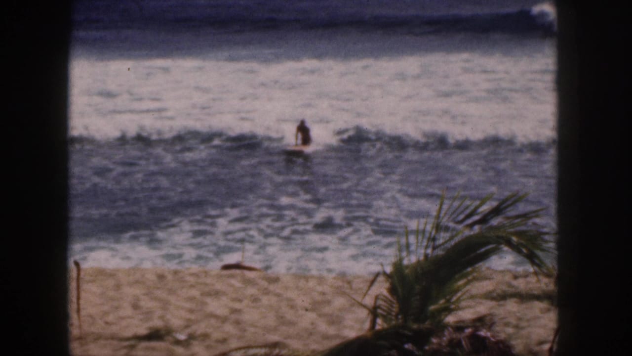 Distant person upright on a board in breaking waves near the shore.