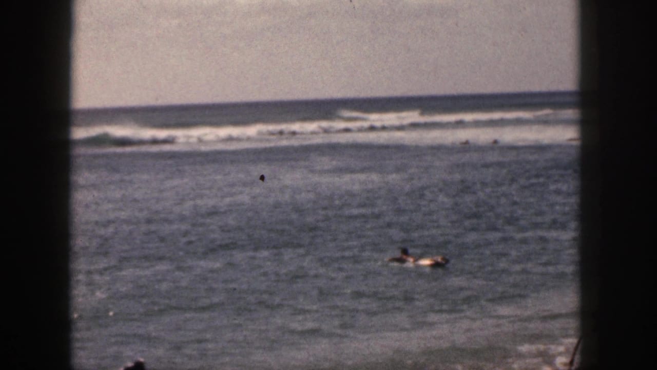 1959 Hawaii ocean frame with distant figures or a board rider at lower right, open water, offshore surf, pale sky, and 8mm grain.