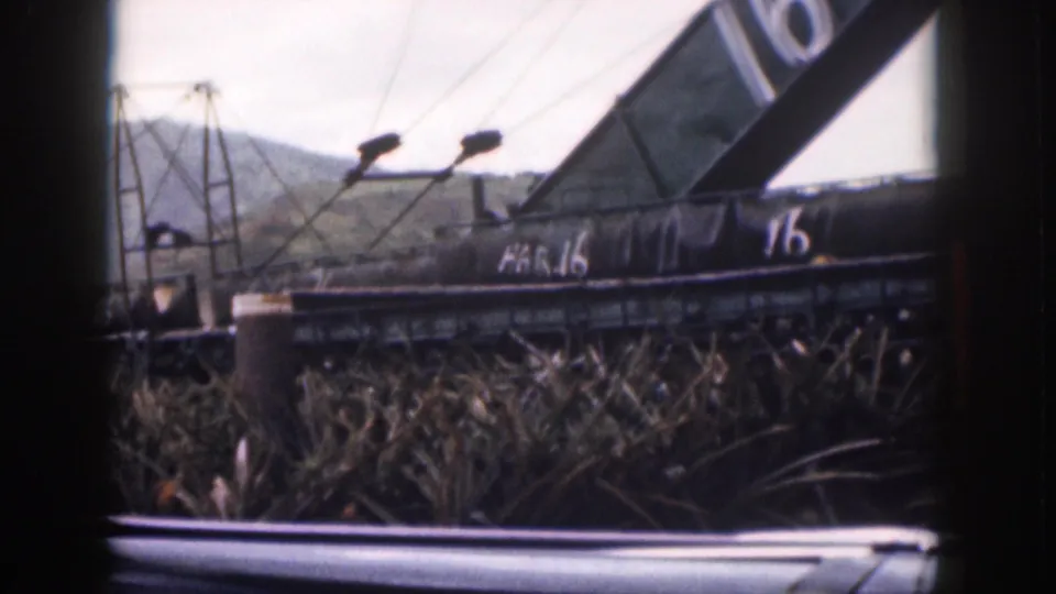 1959 Hawaii 8mm view of a dark structure marked HAR.16 and 16 near reeds, utility poles, and distant hills.