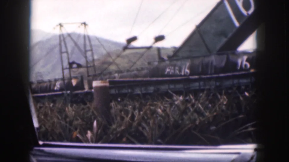 1959 Hawaii frame showing a dark industrial structure marked 16 and HAR.16 behind reeds, with hills beyond.