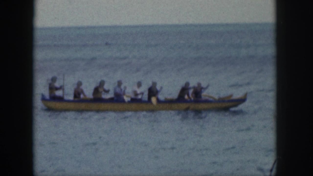 Yellow outrigger canoe with several paddlers crossing calm open water.