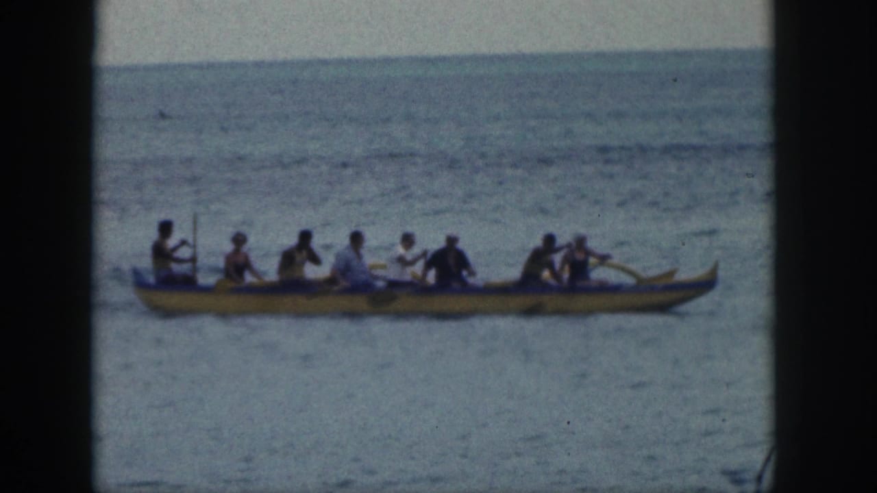 Crew seated in a yellow outrigger canoe paddling on the ocean.