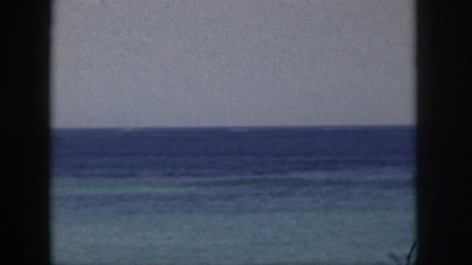 Hawaii coastal home-movie frame from 1959 showing open ocean, turquoise shallows, pale sky, and dark window borders.