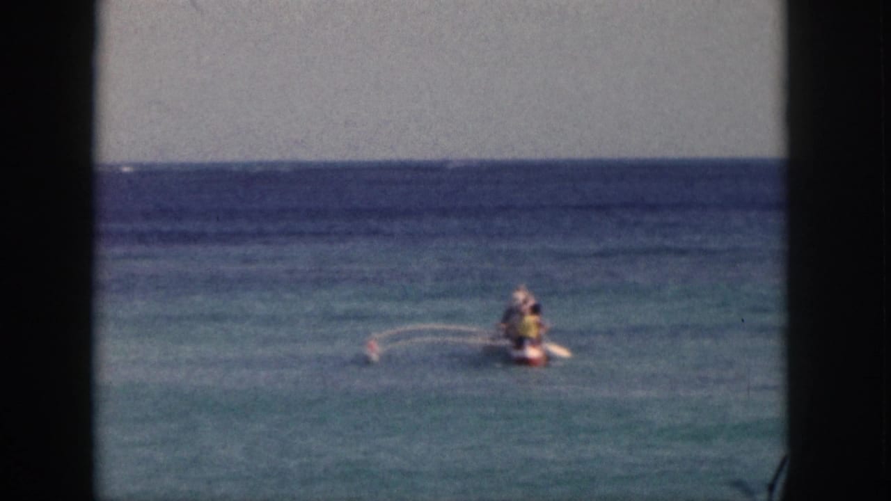 Small kayak or paddle craft on calm ocean water, seen between dark film-frame borders.