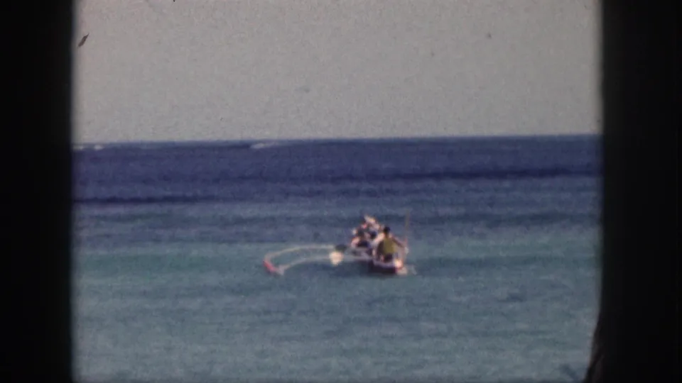 1959 Hawaii 8mm frame showing a small occupied boat on blue-green ocean under a pale sky.