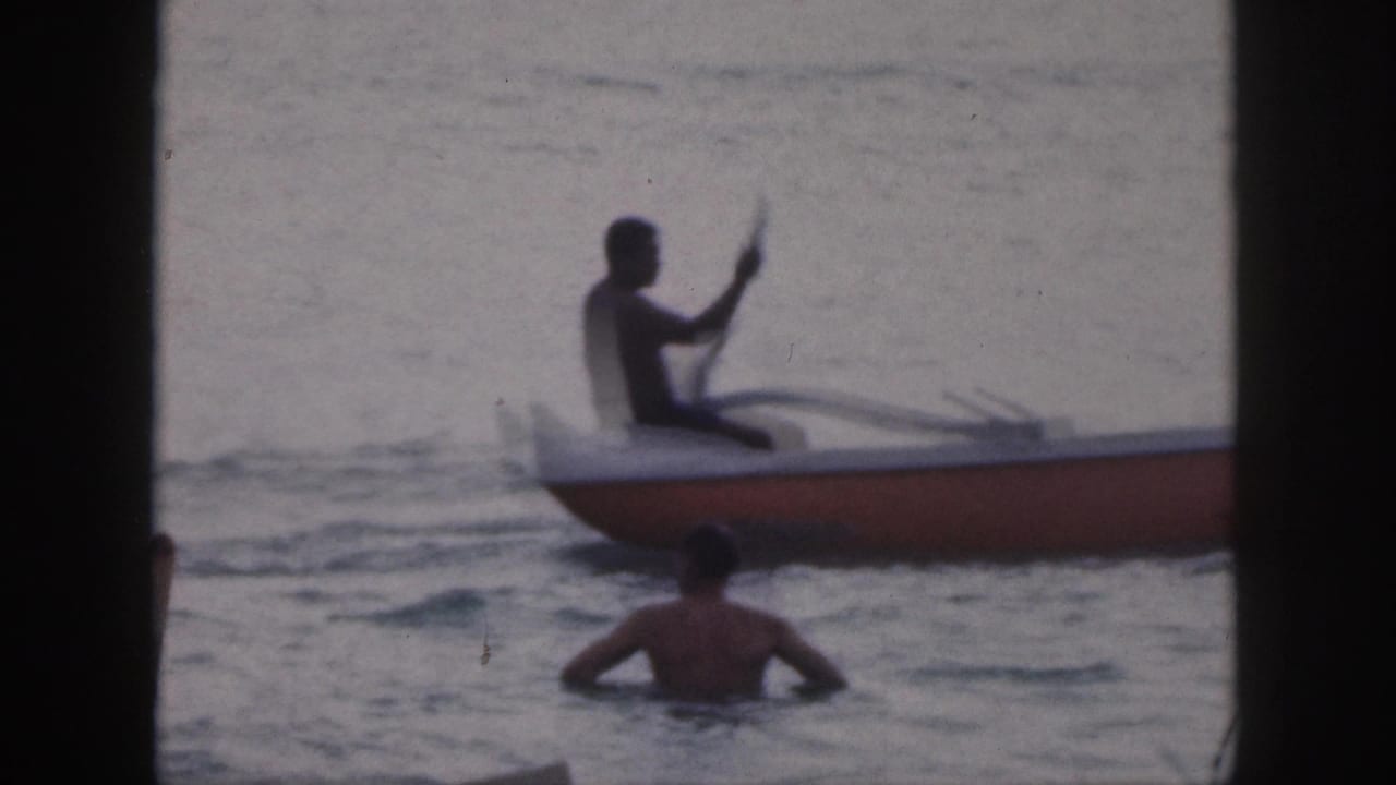 1959 Hawaii 8mm frame with a silhouetted paddler seated in an outrigger canoe and a swimmer in the water.