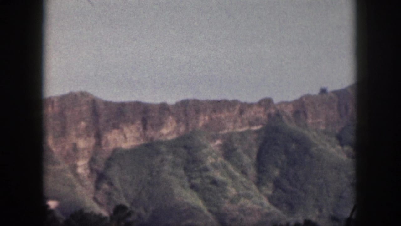 1959 Hawaii 8mm still showing a broad rocky ridge above green slopes, with visible home-movie frame edges.