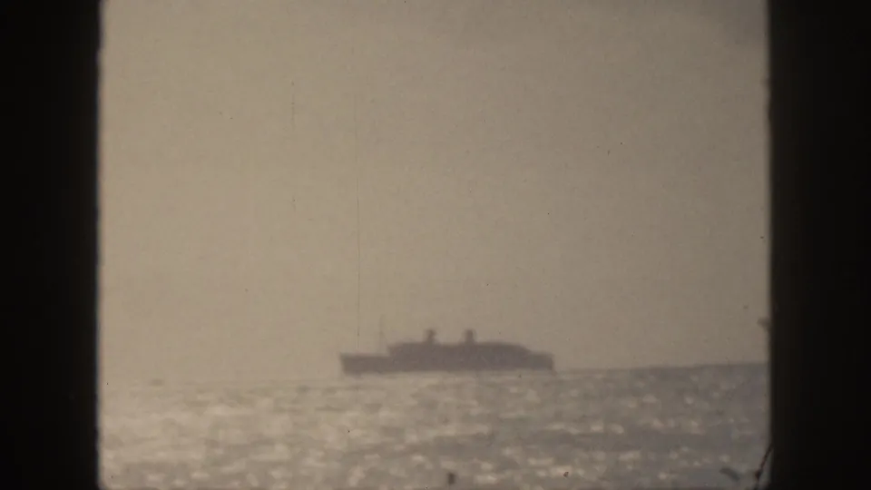 1959 Hawaii home-movie frame showing a distant ship on the horizon, with bright glare across the ocean surface.