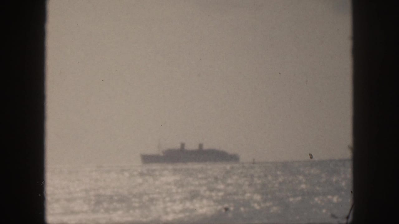 Ocean liner on the horizon with bright water and dark foreground framing.