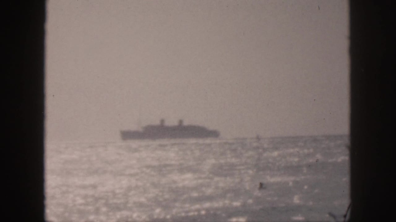 1959 Hawaii 8mm frame showing a far passenger ship on a bright, hazy ocean horizon, viewed through dark vertical framing.