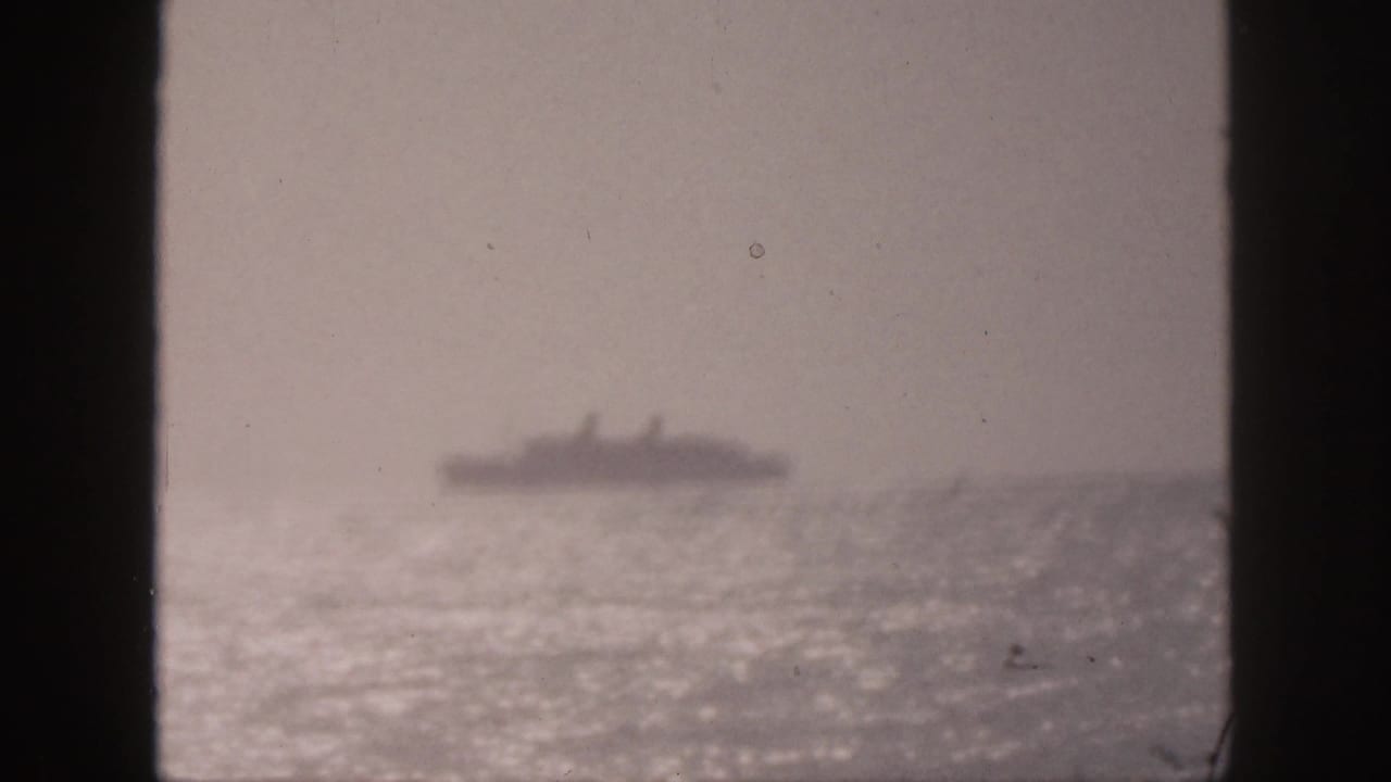 Soft distant ship on a bright ocean horizon with dark vertical borders in the foreground.
