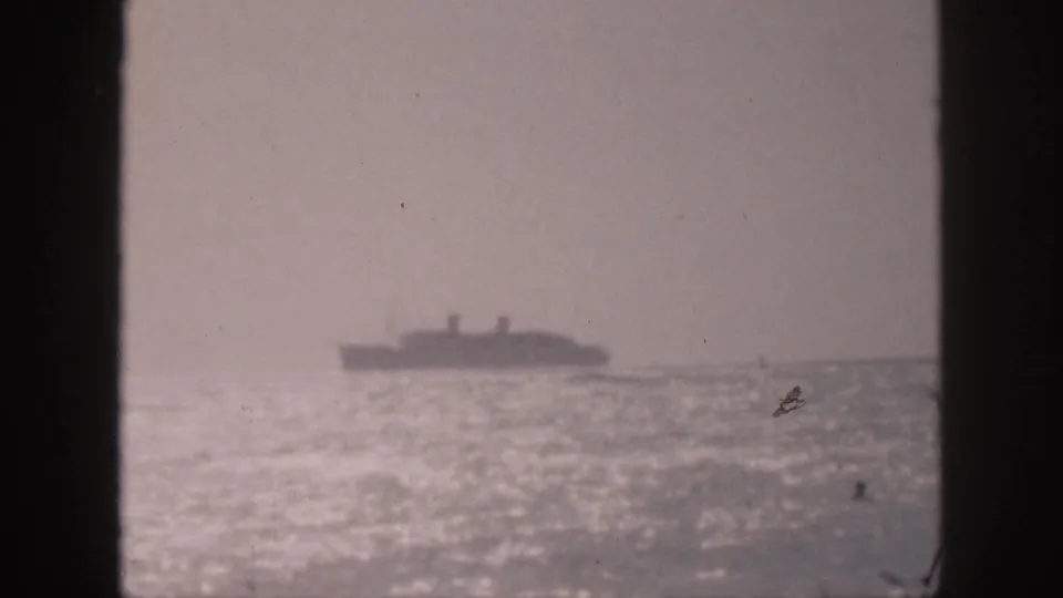 1959 Hawaii 8mm still with a blurred passenger ship on the horizon, bright sea glare, and dark framing along the sides.