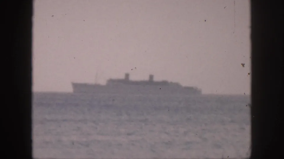 The ship remains distant on the horizon in this soft 8mm Hawaii travel frame, with ocean texture and film grain visible.