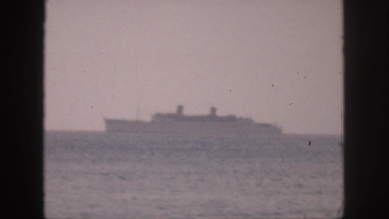 1959 Hawaii 8mm frame showing a distant large ship on the ocean horizon under a hazy sky.