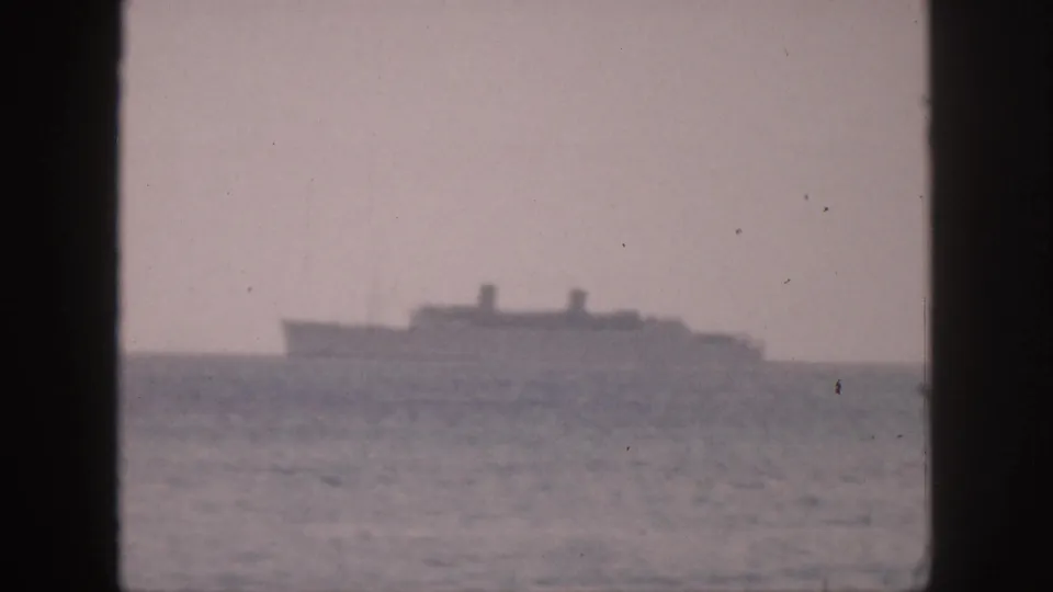 1959 Hawaii 8mm frame showing a distant large ship on the ocean horizon under a hazy sky.