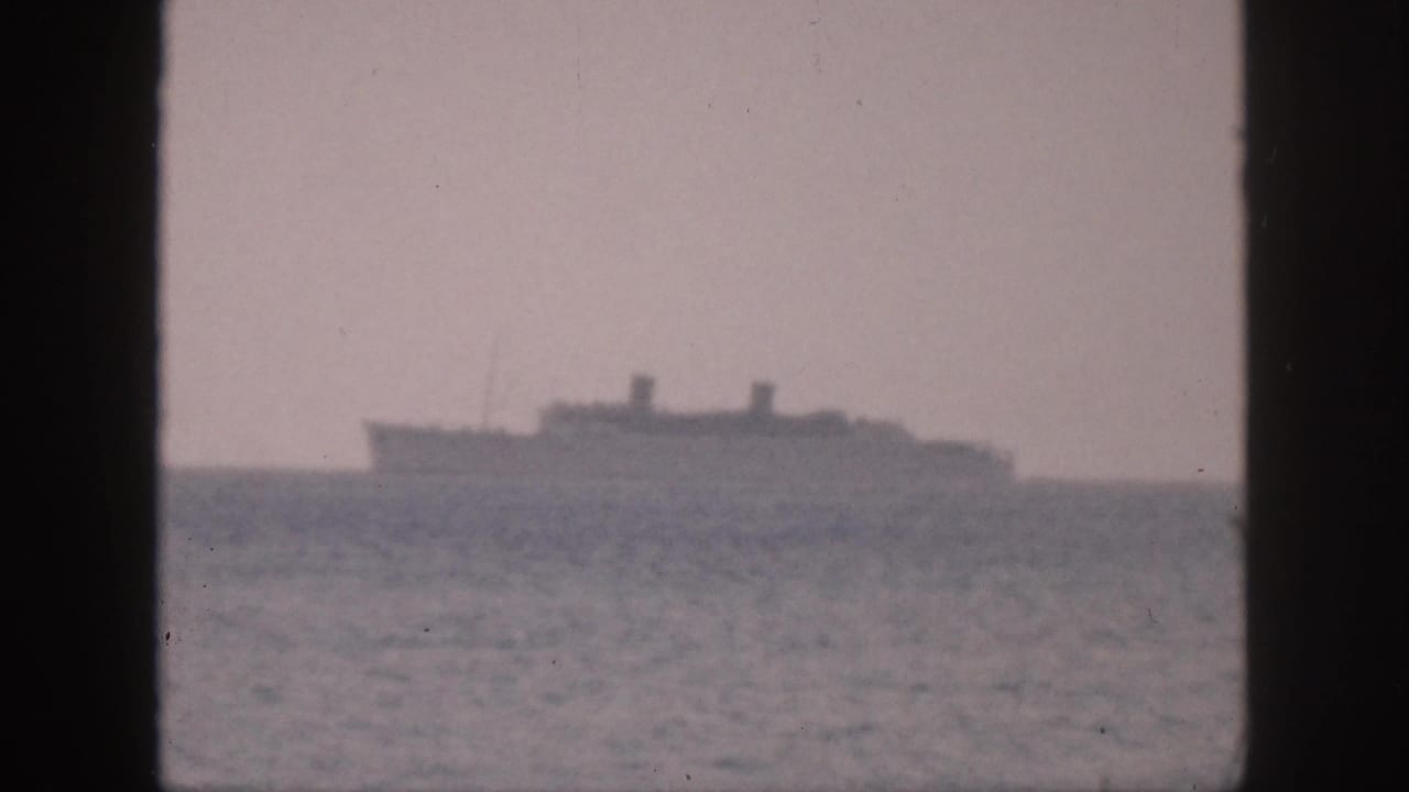 Distant large vessel off Hawaii in 1959, softly rendered by grain and haze in 8mm footage.