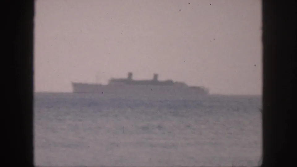1959 Hawaii home-movie frame with a blurred ship silhouette across the ocean horizon.