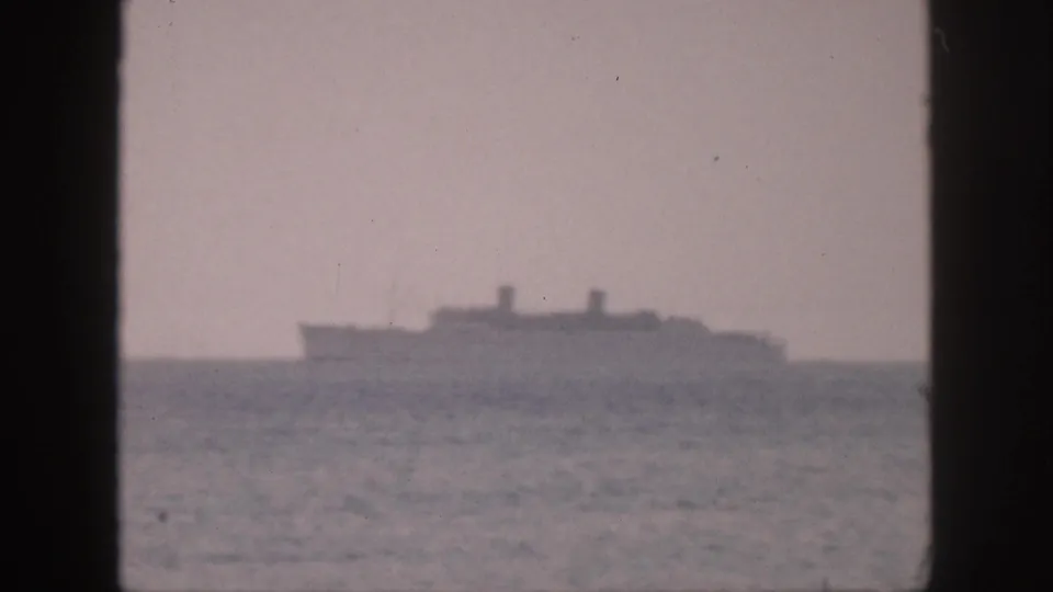 Large ship on the Hawaii horizon in 1959, viewed from a dark-framed 8mm home-movie perspective.