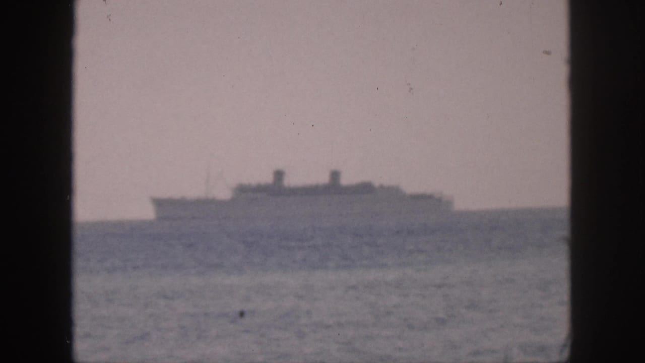 Distant cruise ship or passenger vessel off Hawaii in 1959, framed by a dark central edge and soft 8mm grain.