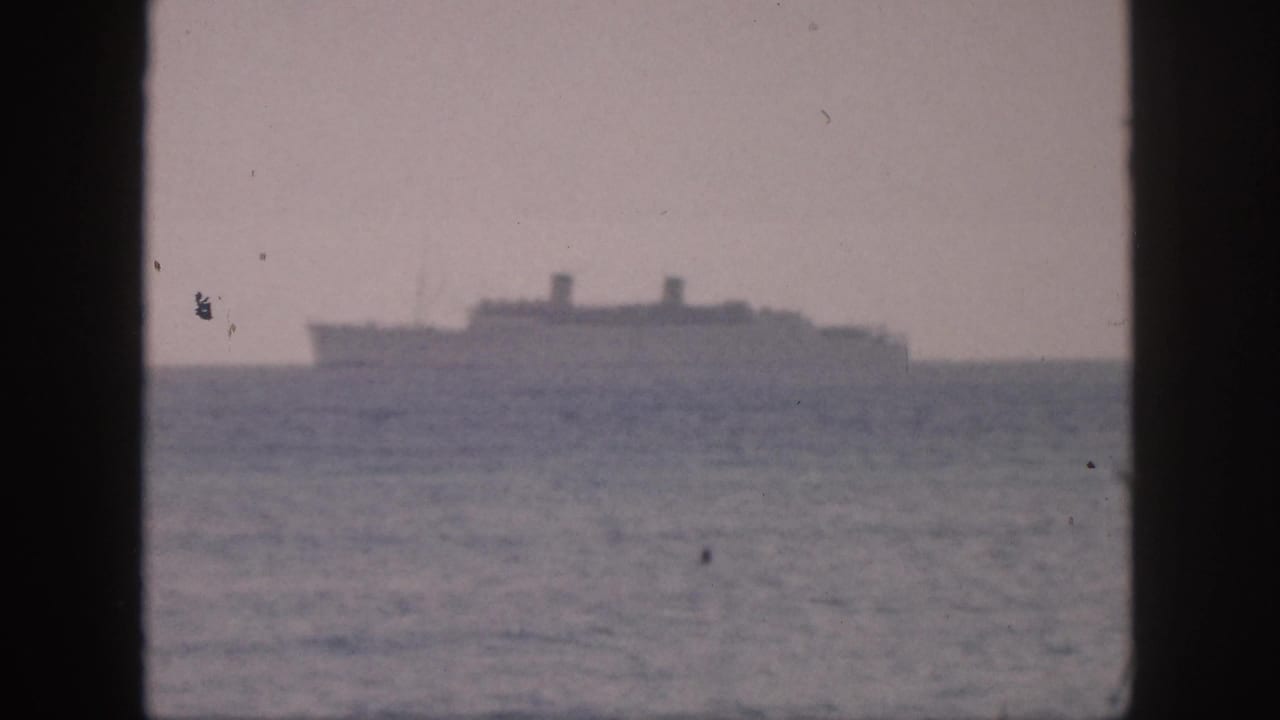 Distant ship on the horizon with ocean in the foreground and dark frame bars at the sides.