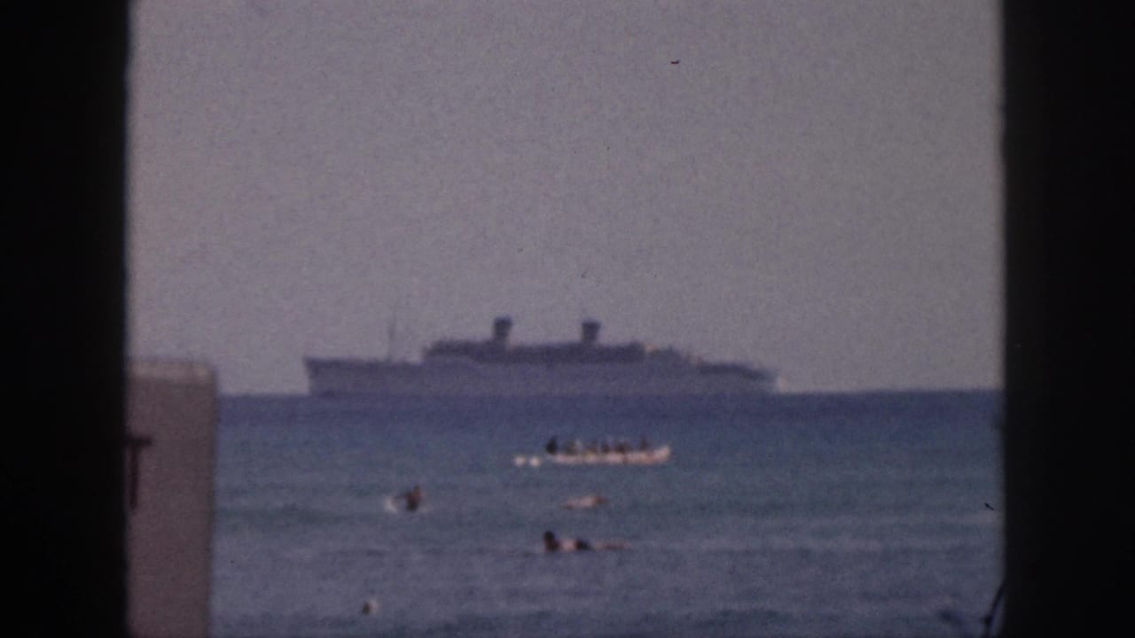 Small boat and swimmers in open water with a distant ship framed by dark borders.