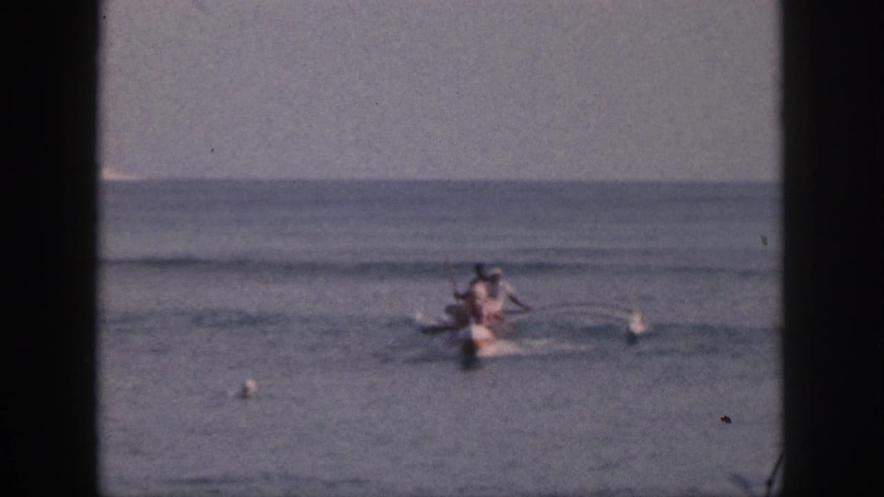 The canoe continues across open Hawaii water, with paddlers, small buoys, and a flat horizon visible in the 8mm frame.