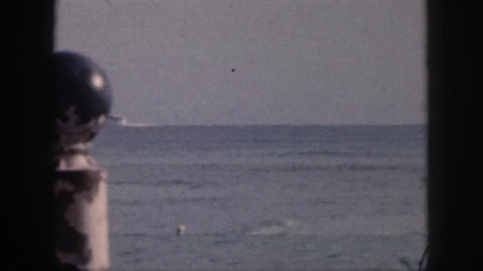 1959 Hawaii 8mm frame looking across calm bay water, with a swimmer and buoy visible through dark window-like framing.