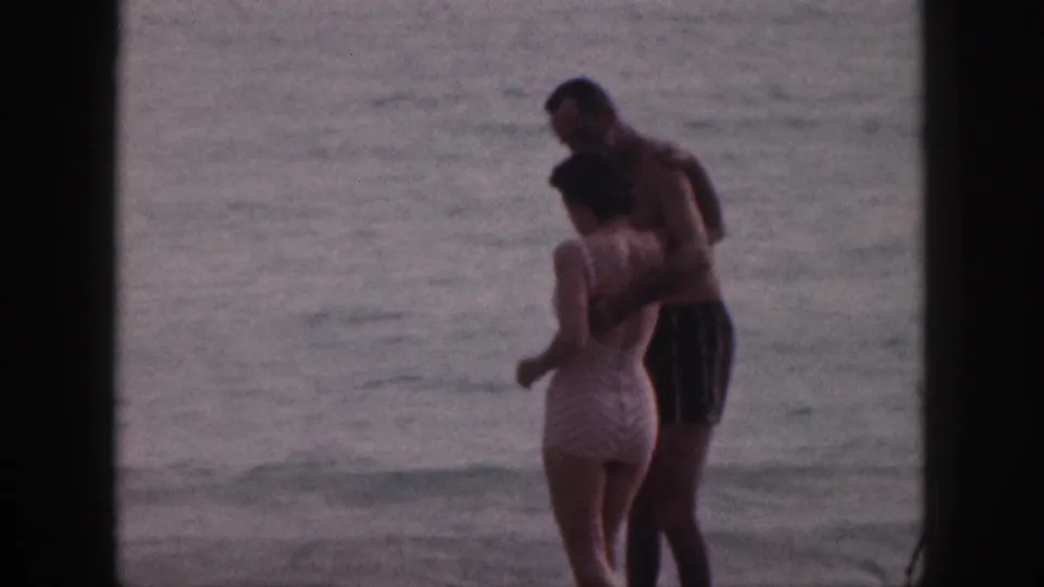The man and woman face each other in the Hawaiian surf, framed by dark edges from the 8mm scan.