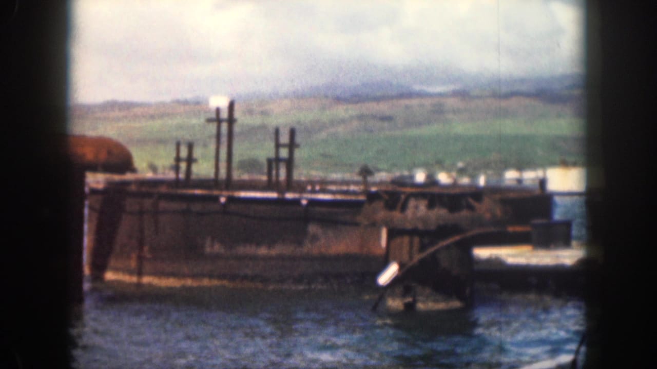 Concrete pier structure in blue water with green hills and cloudy sky beyond.