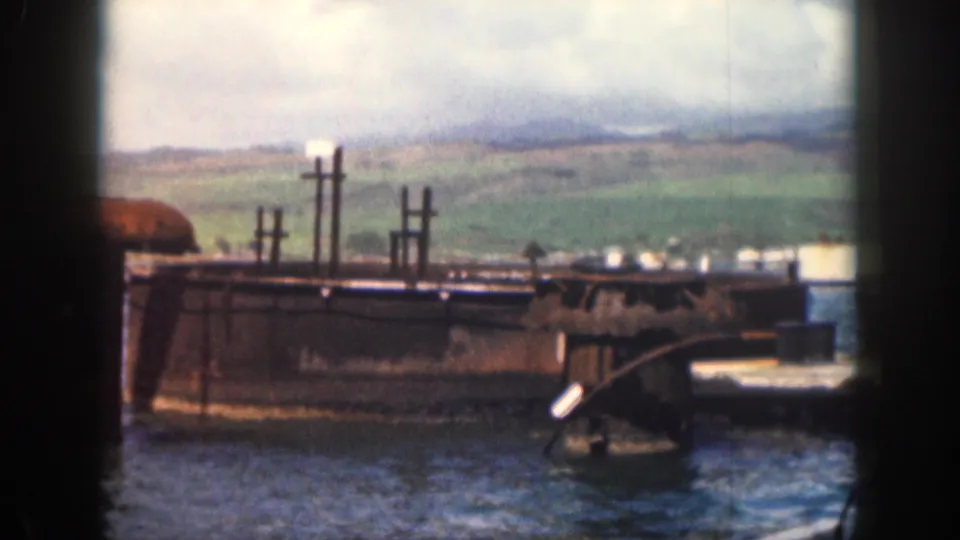 1959 Hawaii 8mm frame showing a concrete pier or breakwater passing by from a boat, with green hills in the distance.