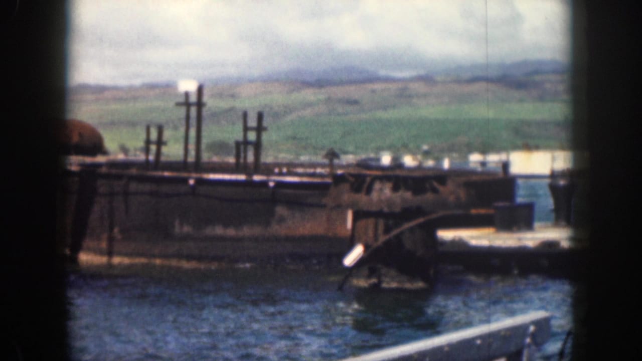 Weathered concrete structure and posts seen across water with hills in the background.