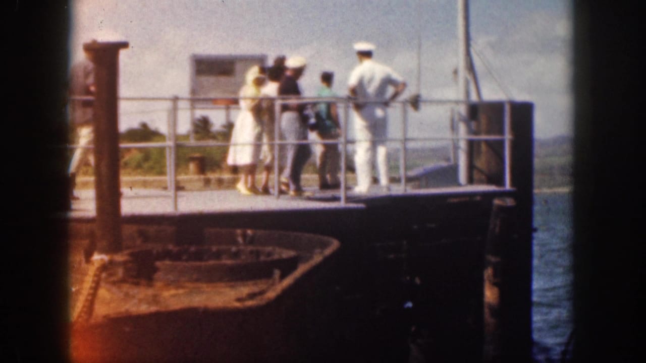 1959 Hawaii home-movie frame showing tourists at a ship railing while a sailor in white uniform stands nearby.