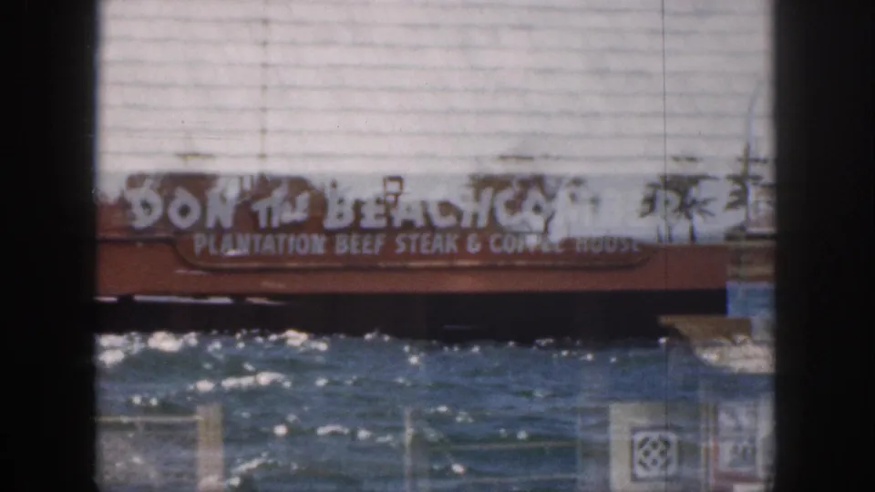 1959 Hawaii 8mm frame with a Don the Beachcomber sign layered over bright water, pier structures, and film gate edges.