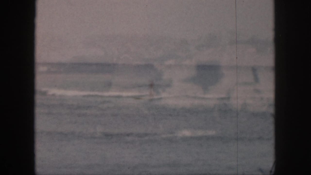 A distant surfer is barely visible in the surf in this faded 1959 Hawaii home-movie frame.