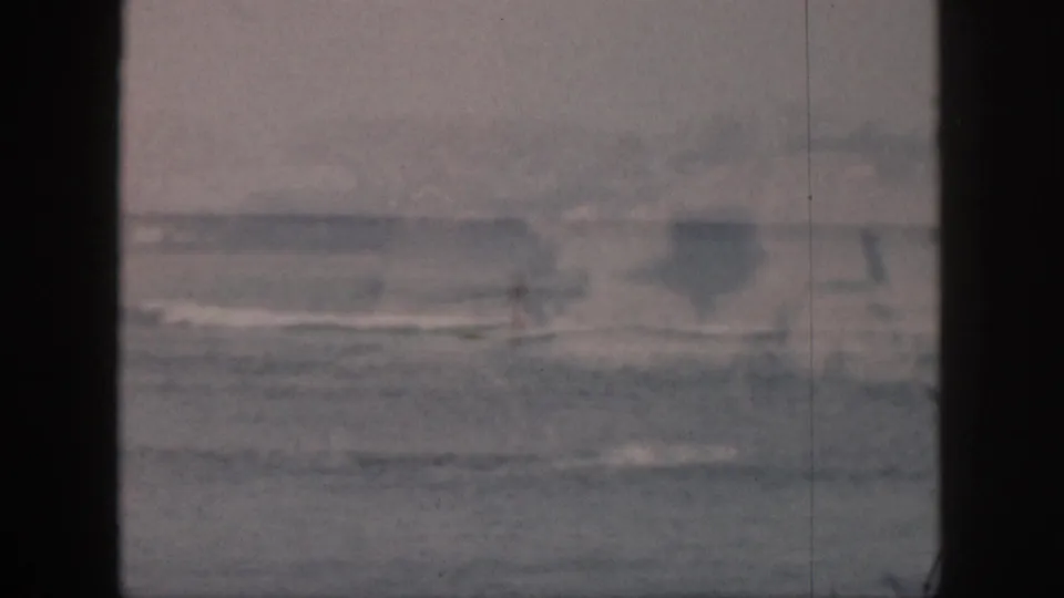 A distant surfer is barely visible in the surf in this faded 1959 Hawaii home-movie frame.