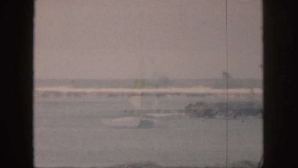 1959 Hawaii 8mm footage shows pale ocean water and distant breaking waves framed by dark window mullions.