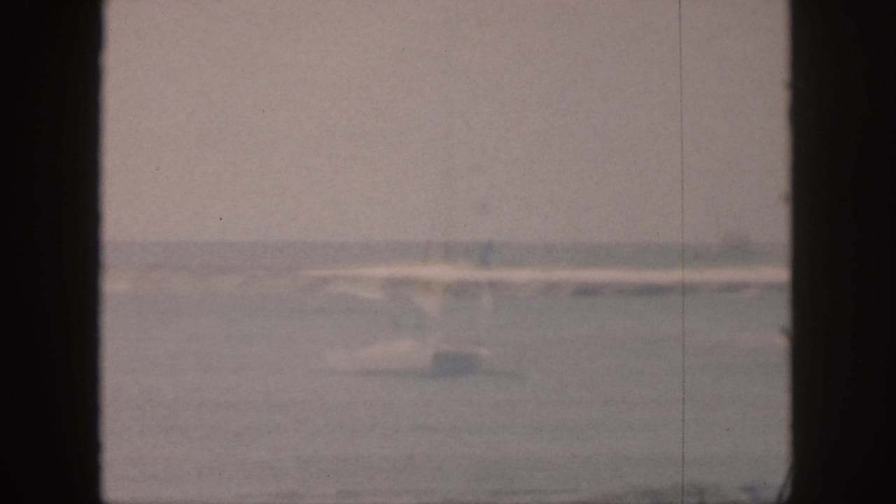 Soft distant waves and shoreline viewed between dark window-frame bars.
