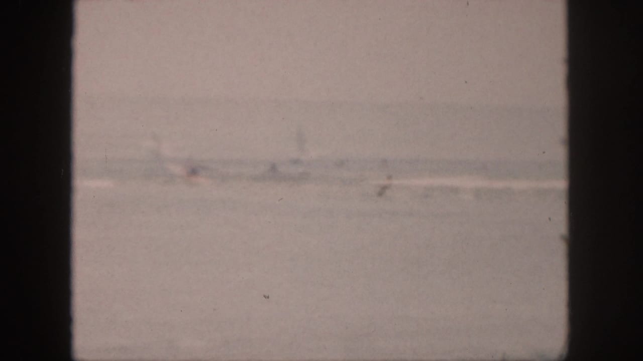 The 1959 Hawaii home-movie frame shows a muted ocean surface, faint surf, and dark window framing.