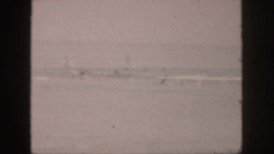 The 1959 Hawaii home-movie frame shows a muted ocean surface, faint surf, and dark window framing.